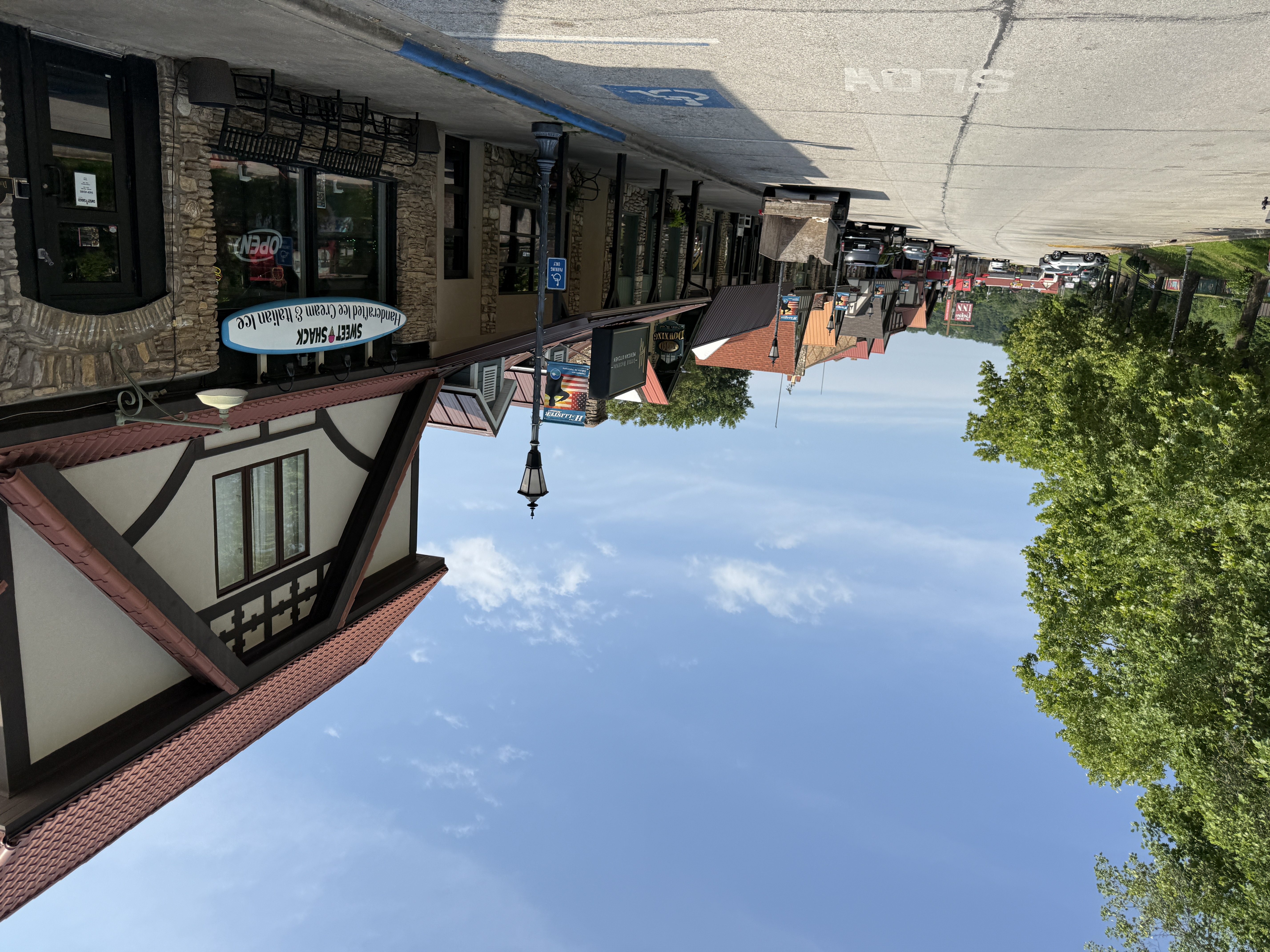 Outdoor view of historic Downing Street in Hollister, MO, featuring stone buildings, red awnings, and a wrought iron patio in front of Downing Street Pour House.