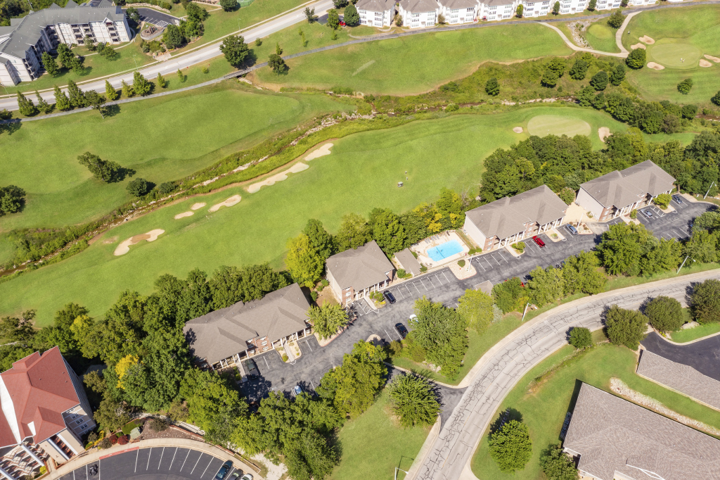 Aerial view of Thousand Hills Golf Course community in Branson Missouri featuring fairways, sand bunkers, nearby condos, parking areas, and a community pool.