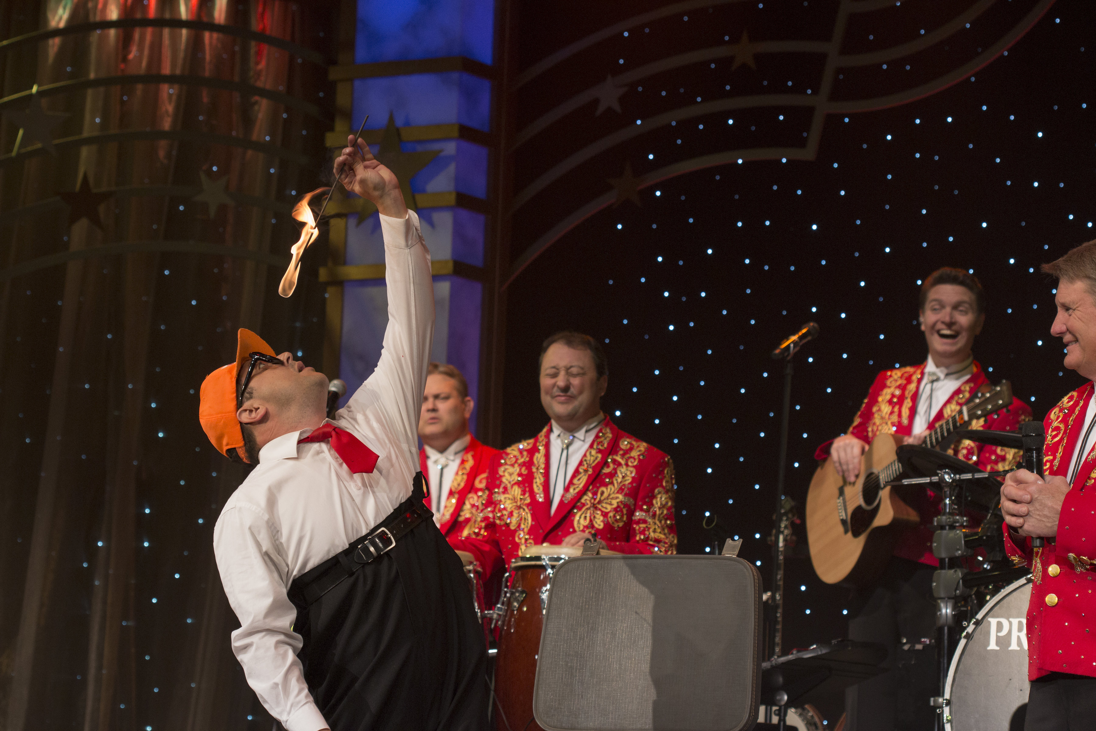 Performer swallowing a flaming object on stage during a live show in Branson Missouri with musicians in red jackets playing instruments in the background