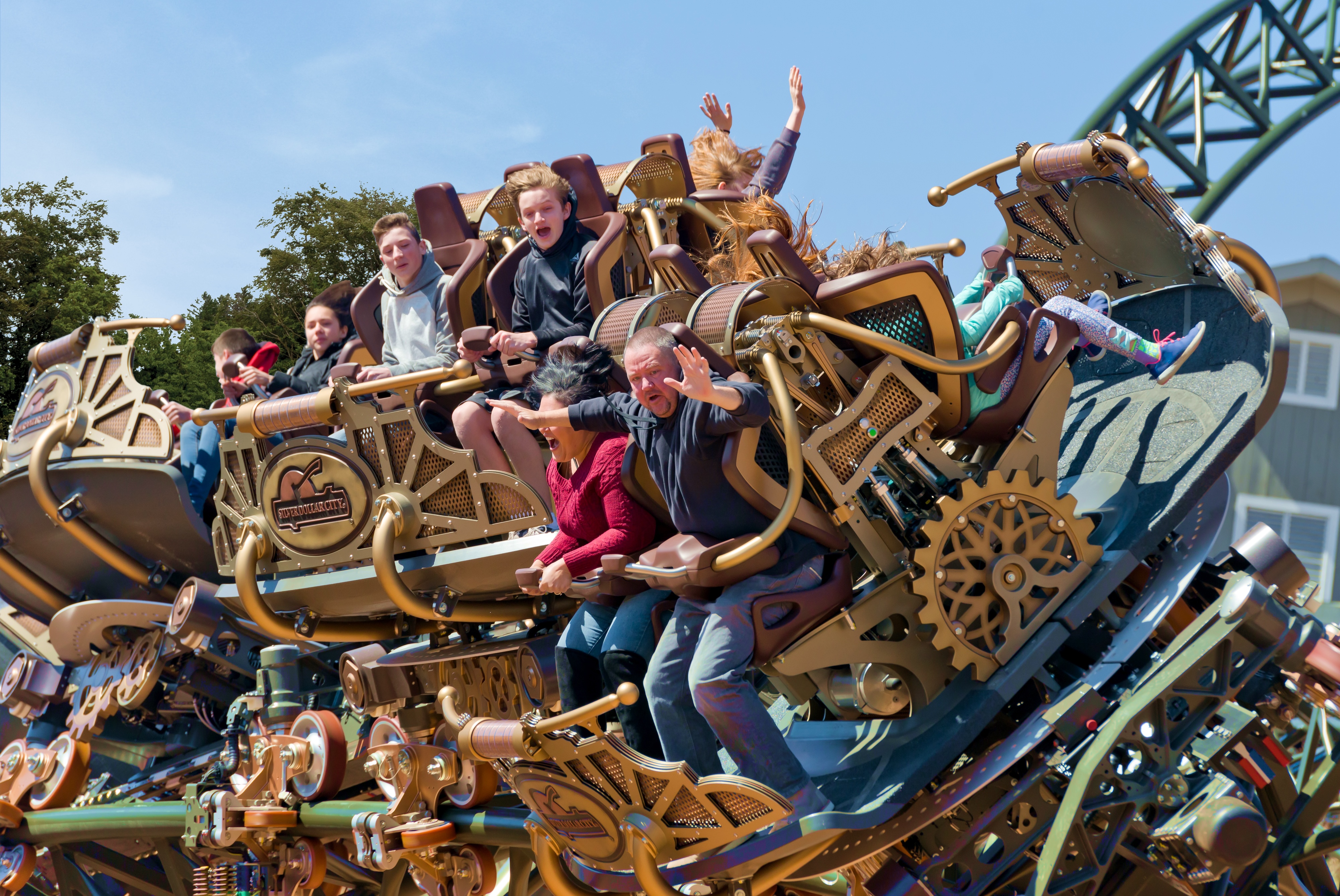 Family riding a roller coaster at Silver Dollar City in Branson Missouri with hands raised and Ozark hills in the background
