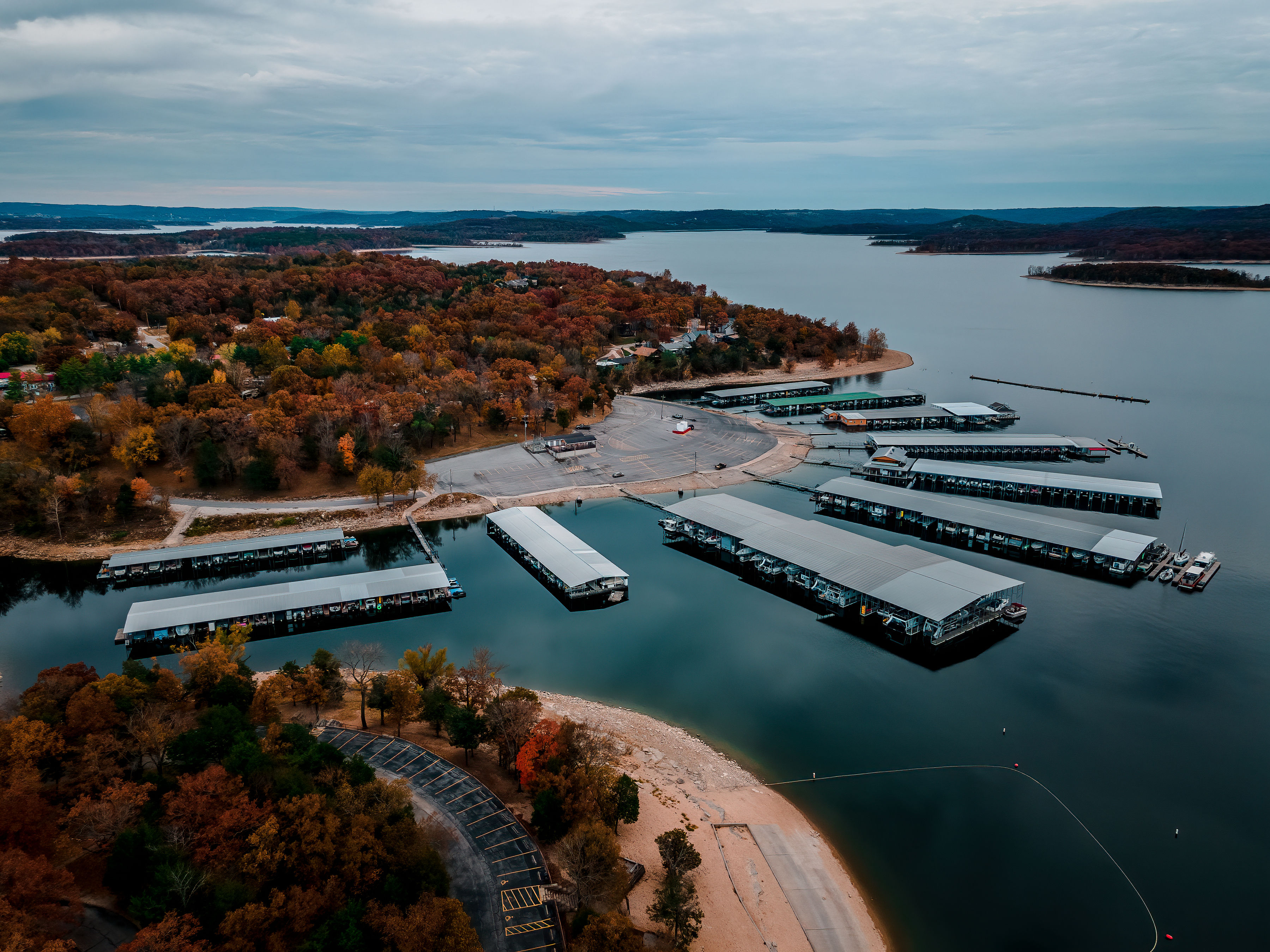 Aerial view of a marina on Table Rock Lake near Branson Missouri with covered boat docks, shoreline, and autumn trees surrounding the water.