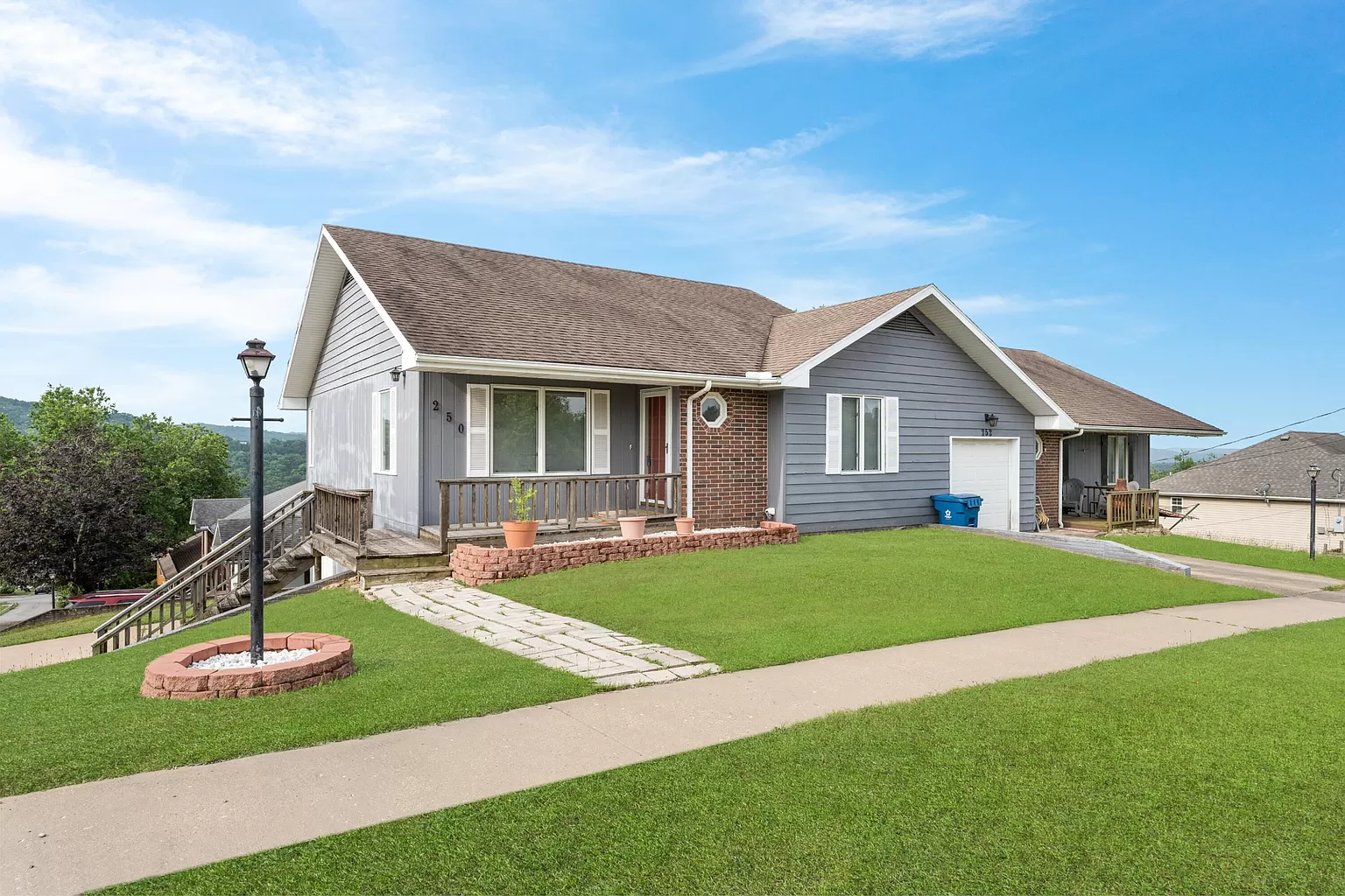 Single-story home with gray siding, brick accents, front porch, and attached garage in Branson, Missouri.