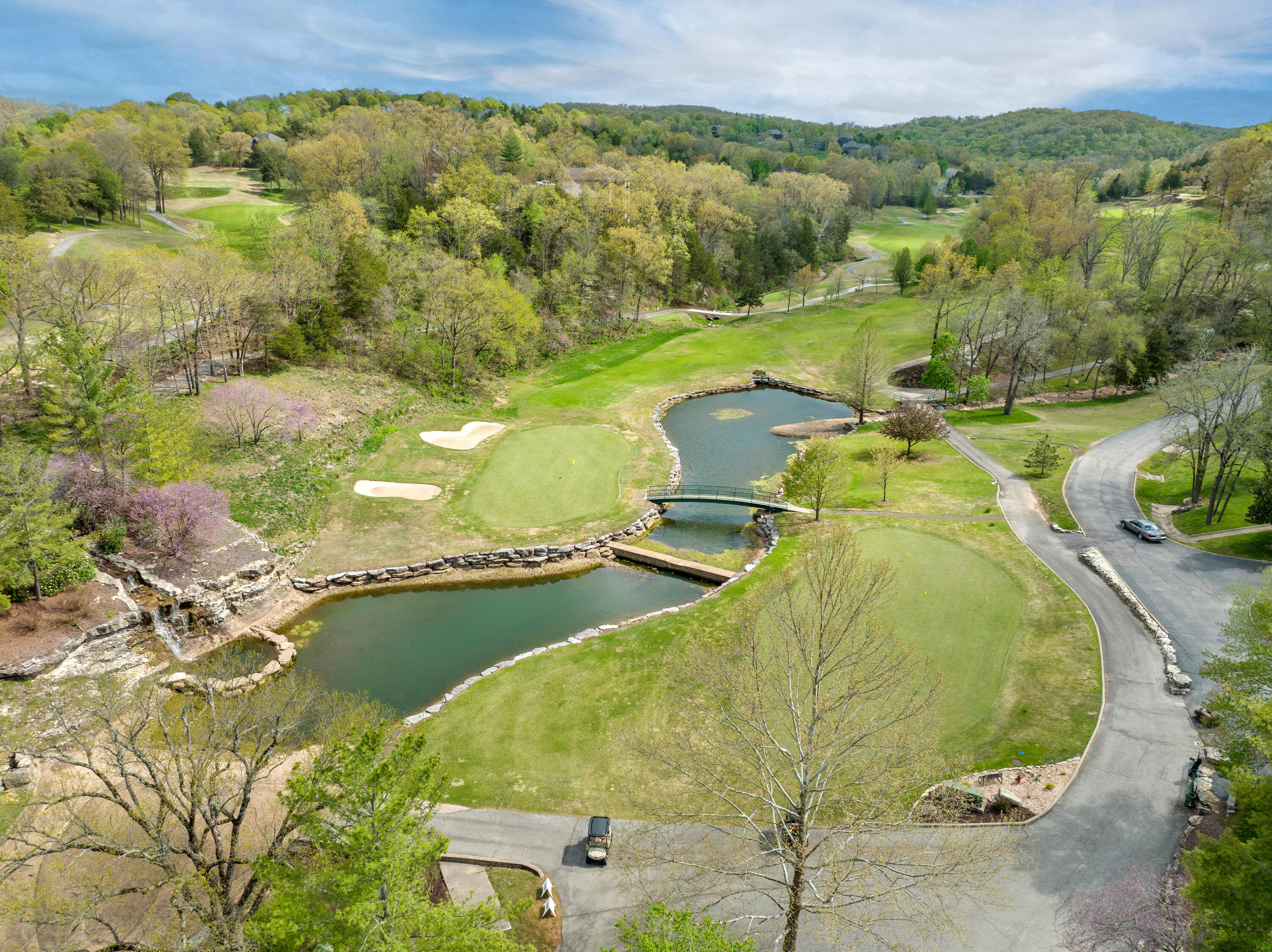 Aerial view of Ledgestone Golf Course in StoneBridge Village near Branson, Missouri featuring rolling Ozark hills, manicured fairways, sand bunkers, small bridges, and water features.