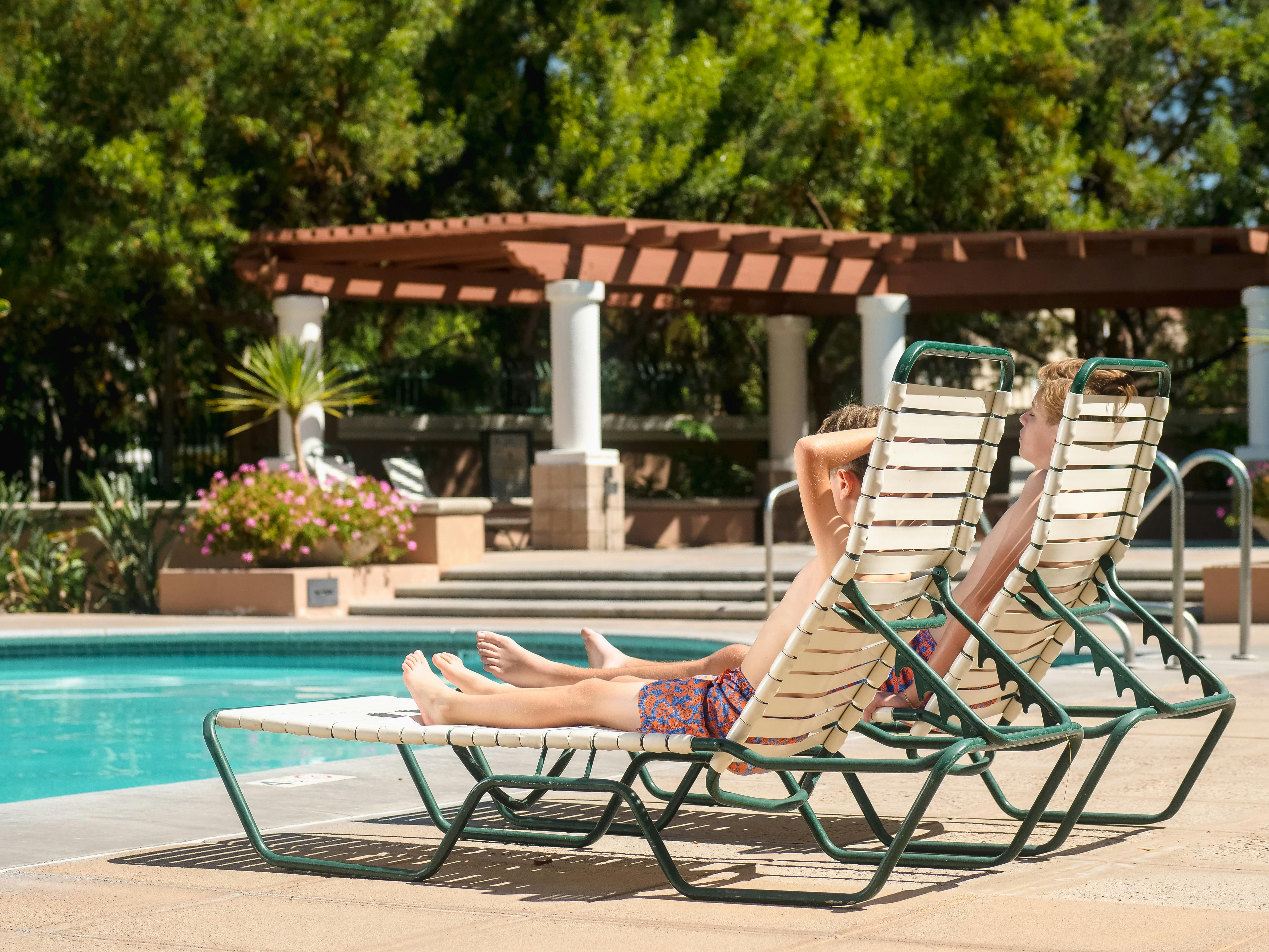Community swimming pool with lounge chairs and pergola seating area.