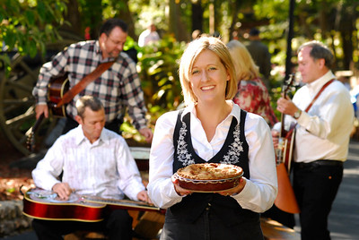 Silver Dollar City employee holding a fresh pie with live bluegrass musicians performing in Branson, Missouri.