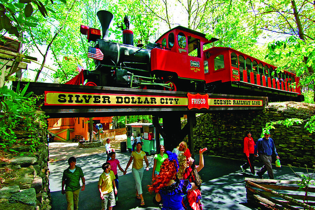 Visitors walking beneath the Frisco Scenic Railway train at Silver Dollar City theme park in Branson, Missouri.